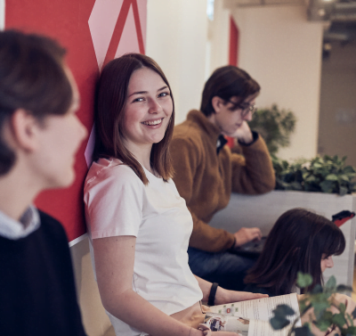 Elev sitter pa en bank i skolan och ler in i kameran.