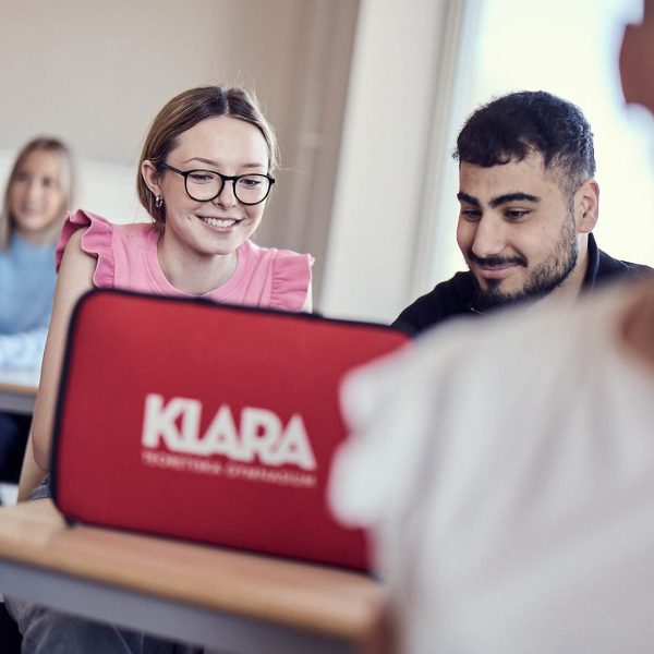 Tva elever i ett klassrum tittar ned i en dator.
