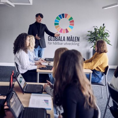 Larare undervisar framme vid tavlan i ett klassrum.
