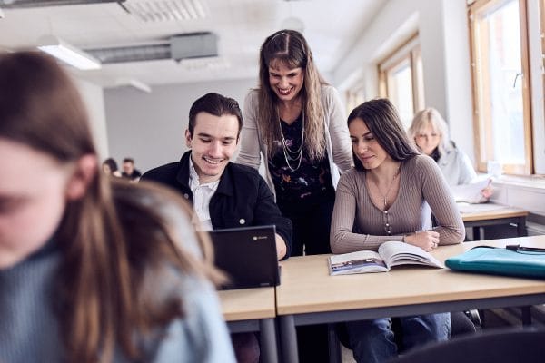 En larare hjalper tva elever i klassrummet.