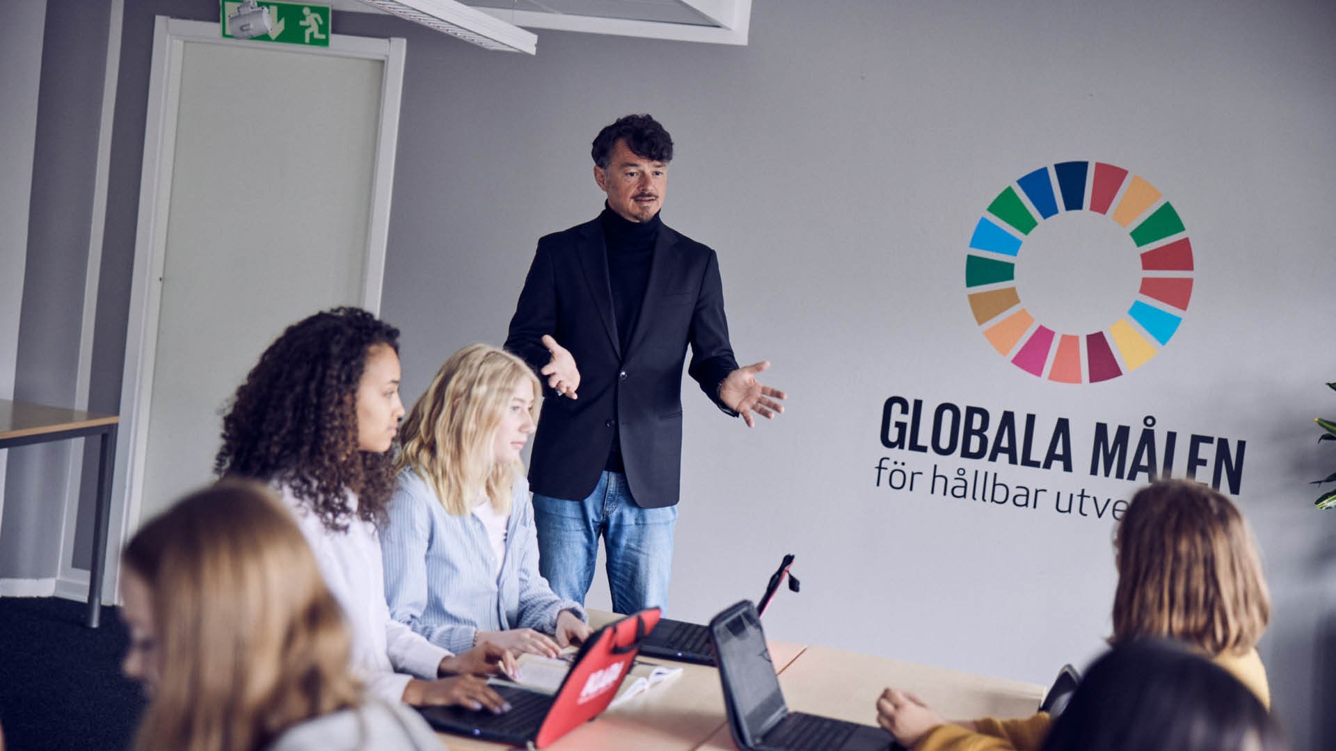 Larare och elever i ett klassrum med vaggen tackt av globala mal.