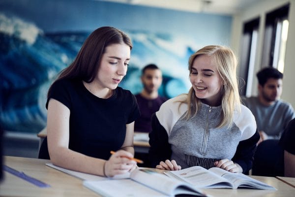 Tva elever sitter tillsammans och loser en uppgift i matematik.