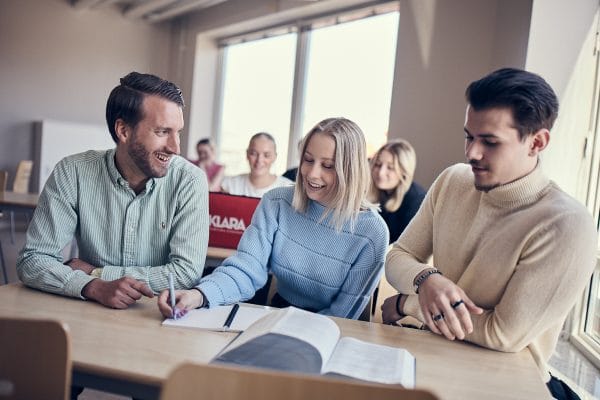 Tva glada elever far hjalp med en uppgift av en larare.