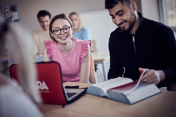 Tva glada elever sitter med lagboken och funderar.