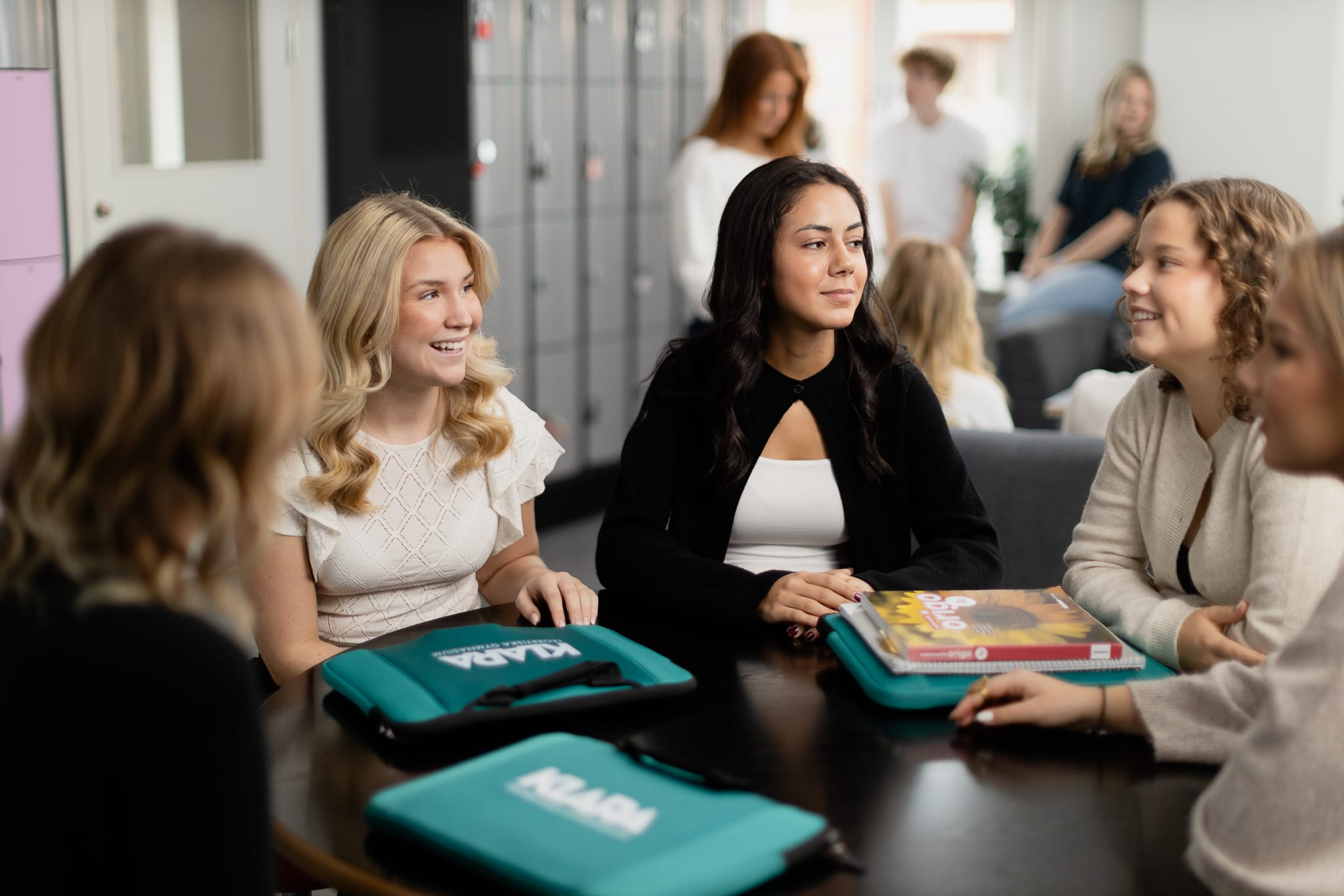Nagra elever sitter och pratar runt ett bord pa rasten.